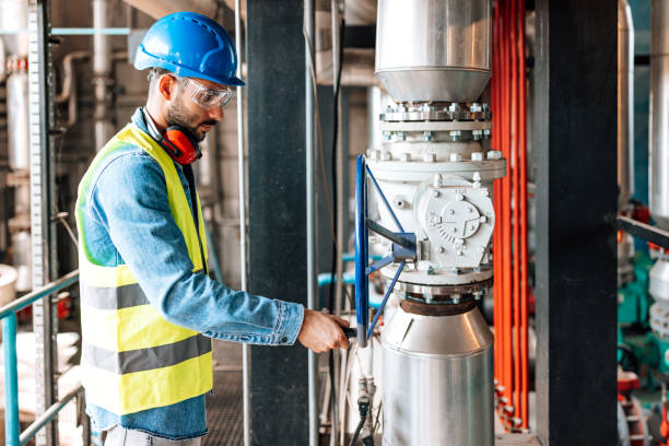 a young caucasian male engineer is checking a valve in a heating plant.